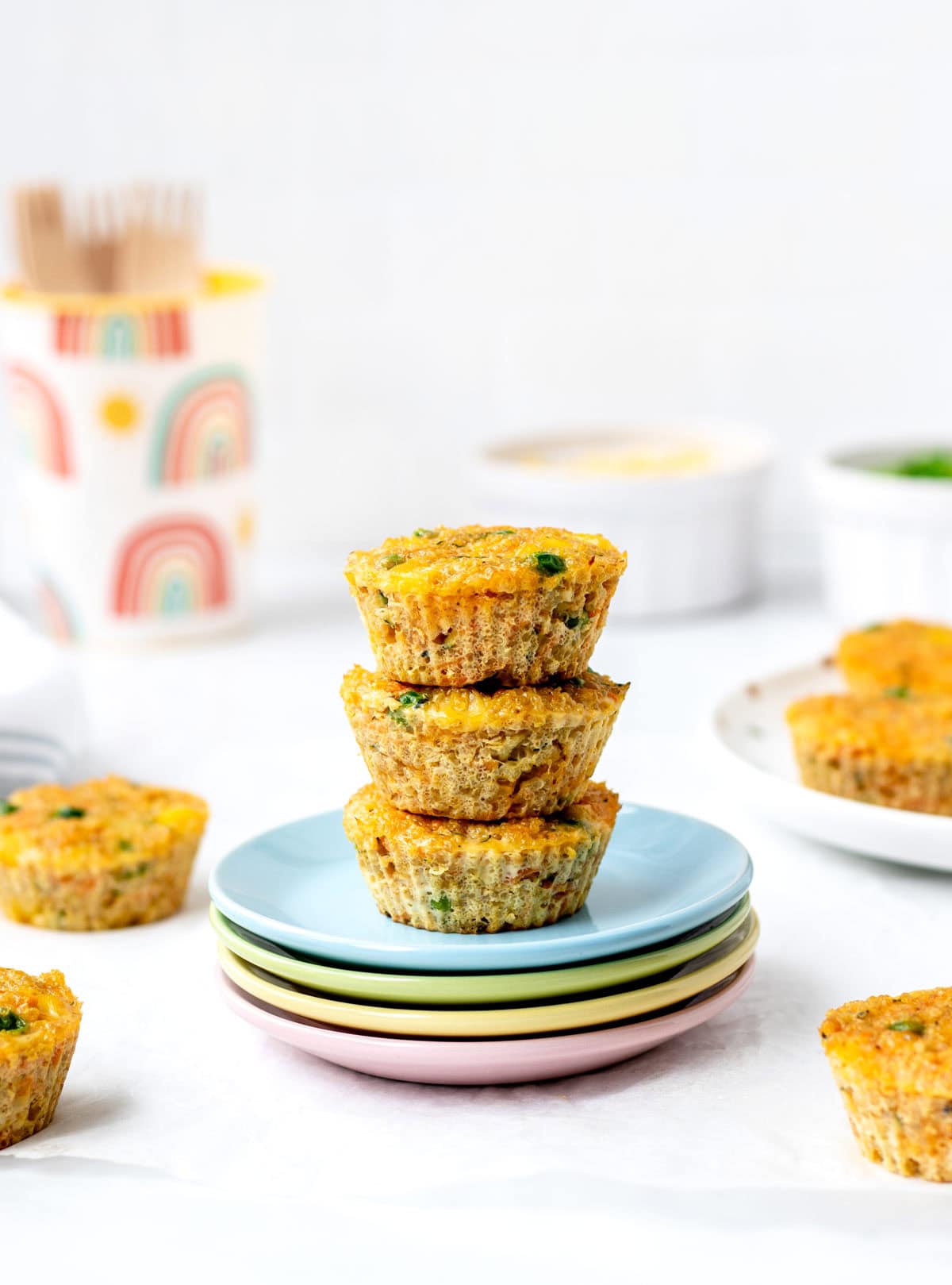 Three quinoa veggie cups stacked on colorful plates.