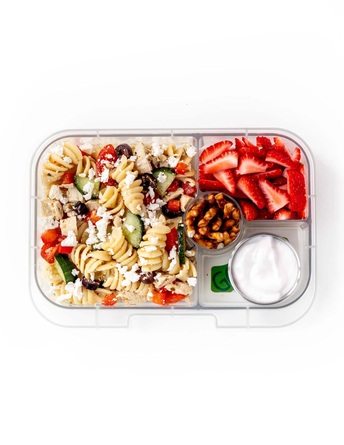 A lunchbox filled with veggie pasta salad, strawberries, nuts and Greek yogurt.