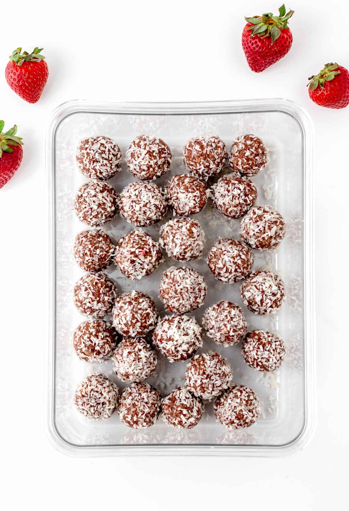 Fully assembled strawberry bliss balls on a baking sheet lined with parchment paper.