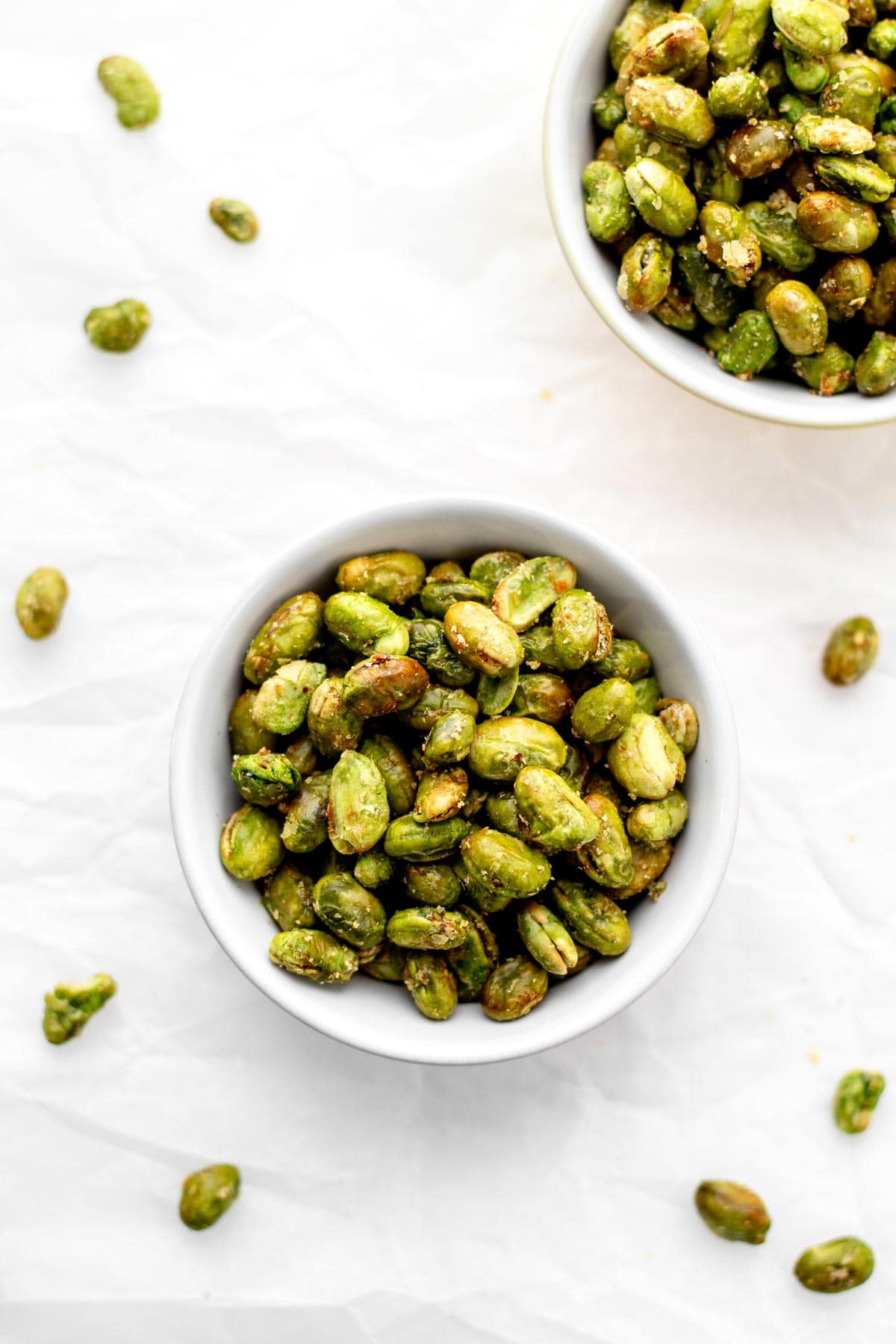 Two bowls of air fryer edamame on a table.