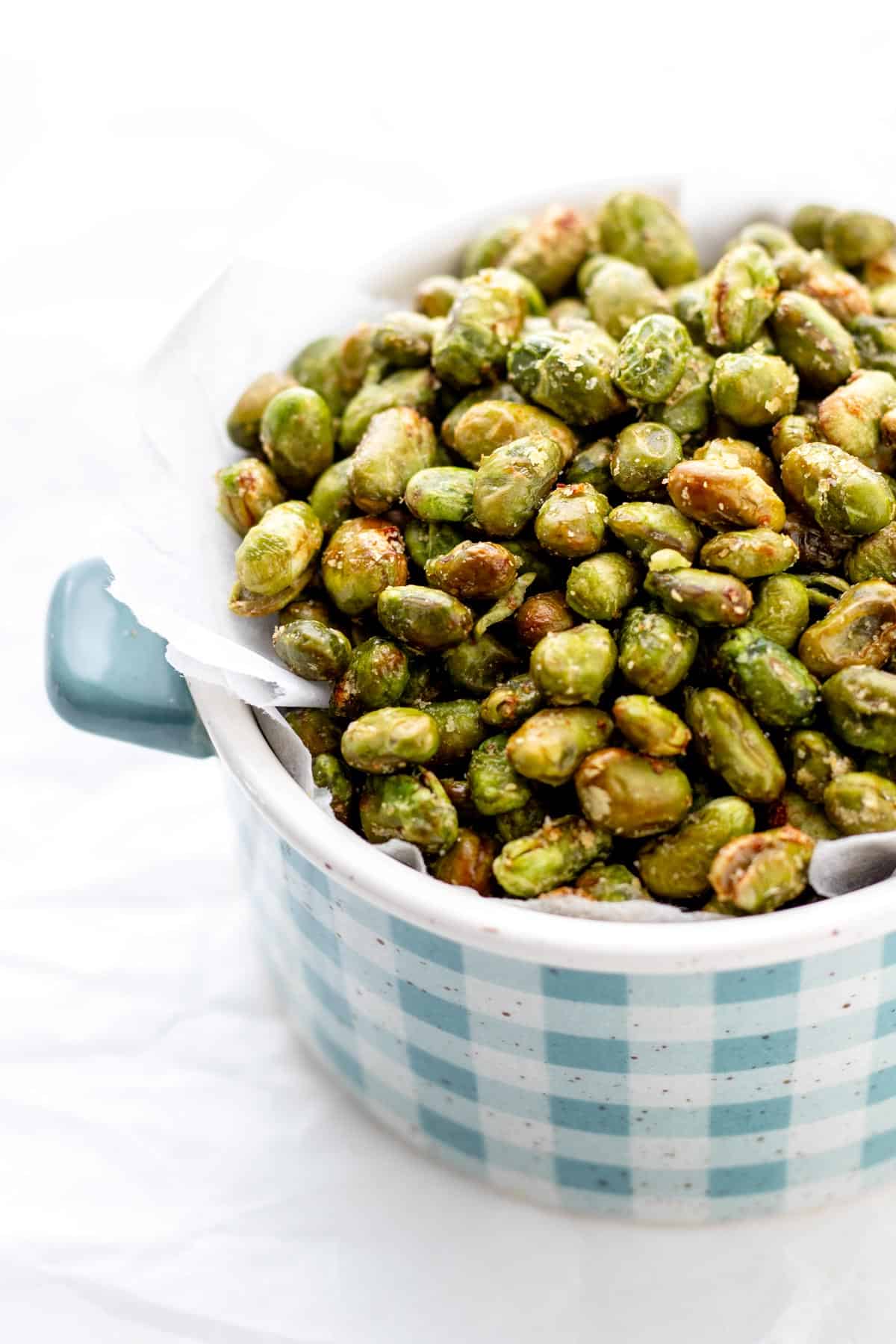 Air fryer edamame in a blue and white plaid bowl.