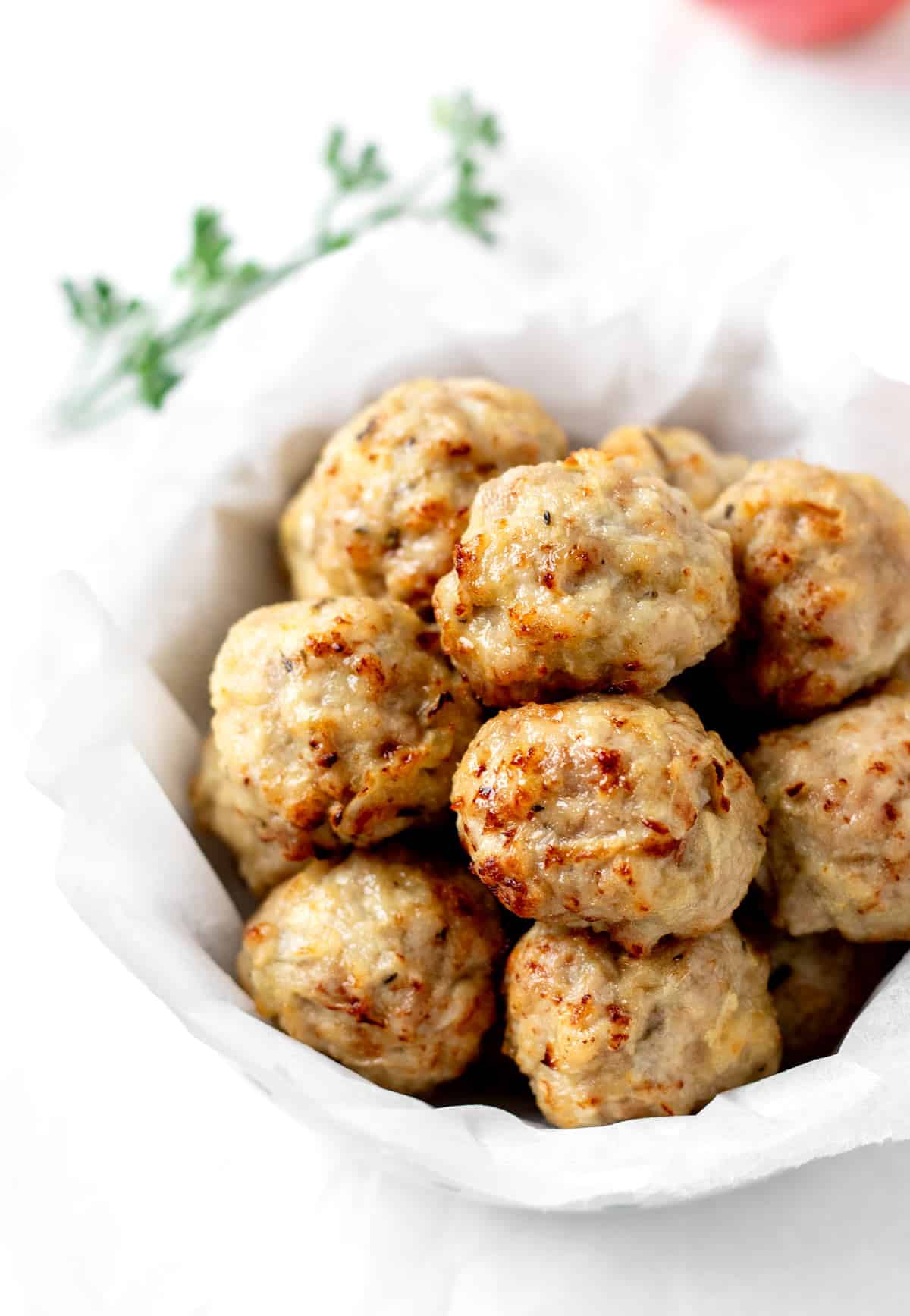 Apple and chicken meatballs in a bowl on a table.