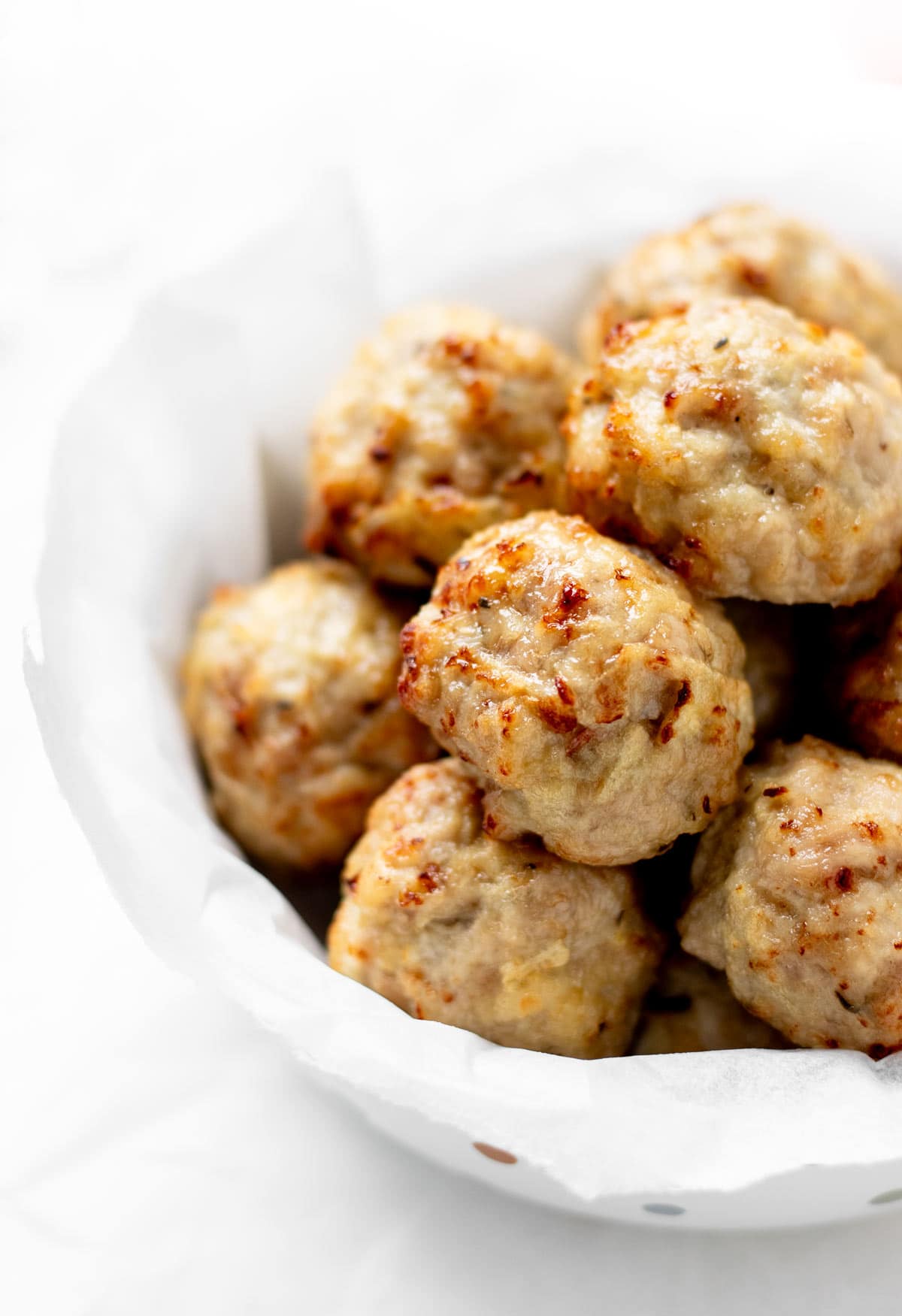 A sideview of a bowl of apple and chicken meatballs.