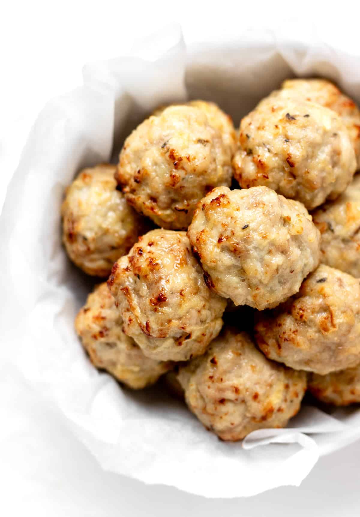 Apple and chicken meatballs in a white bowl.