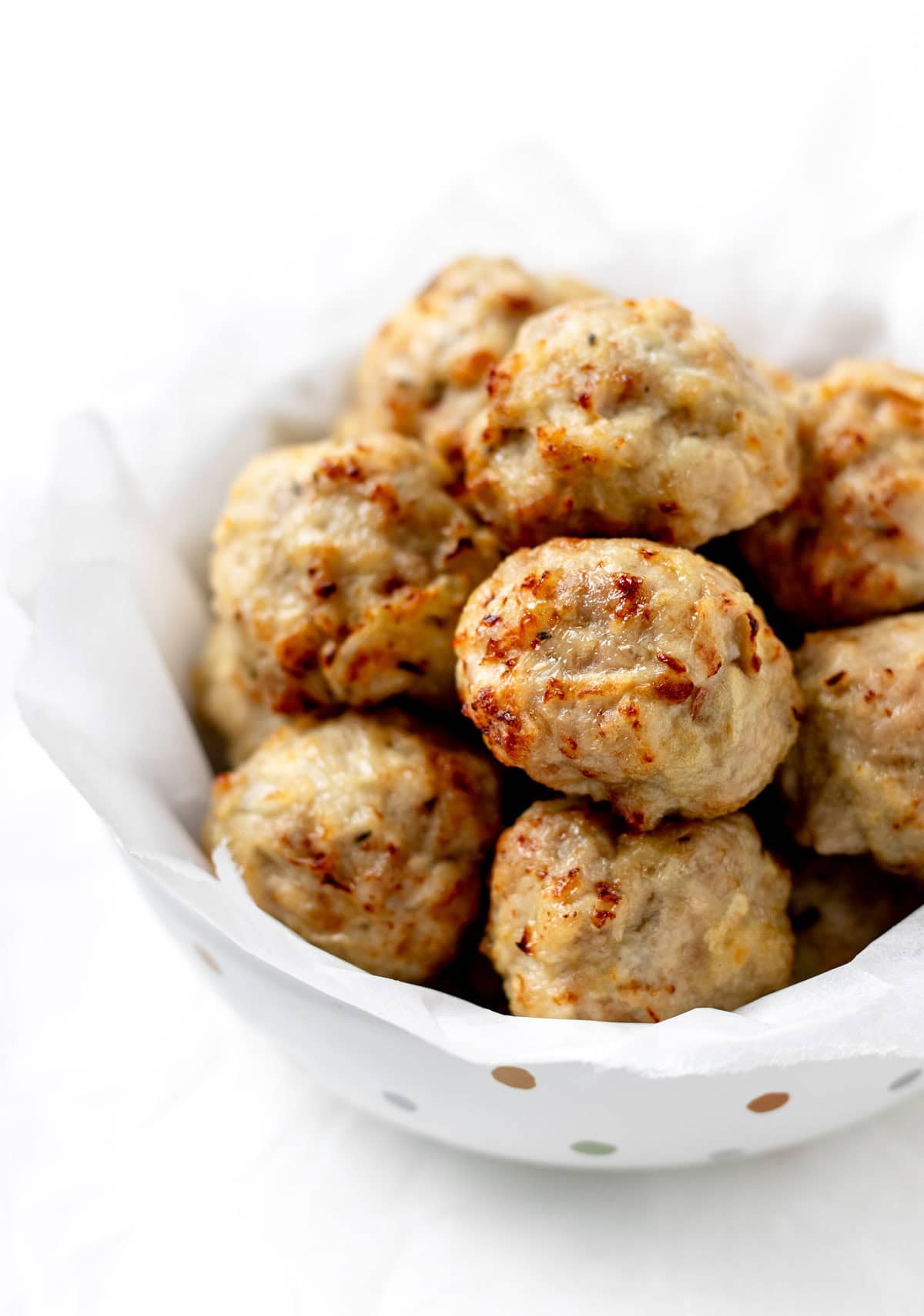 A close-up of apple chicken meatballs in a polka dot bowl.