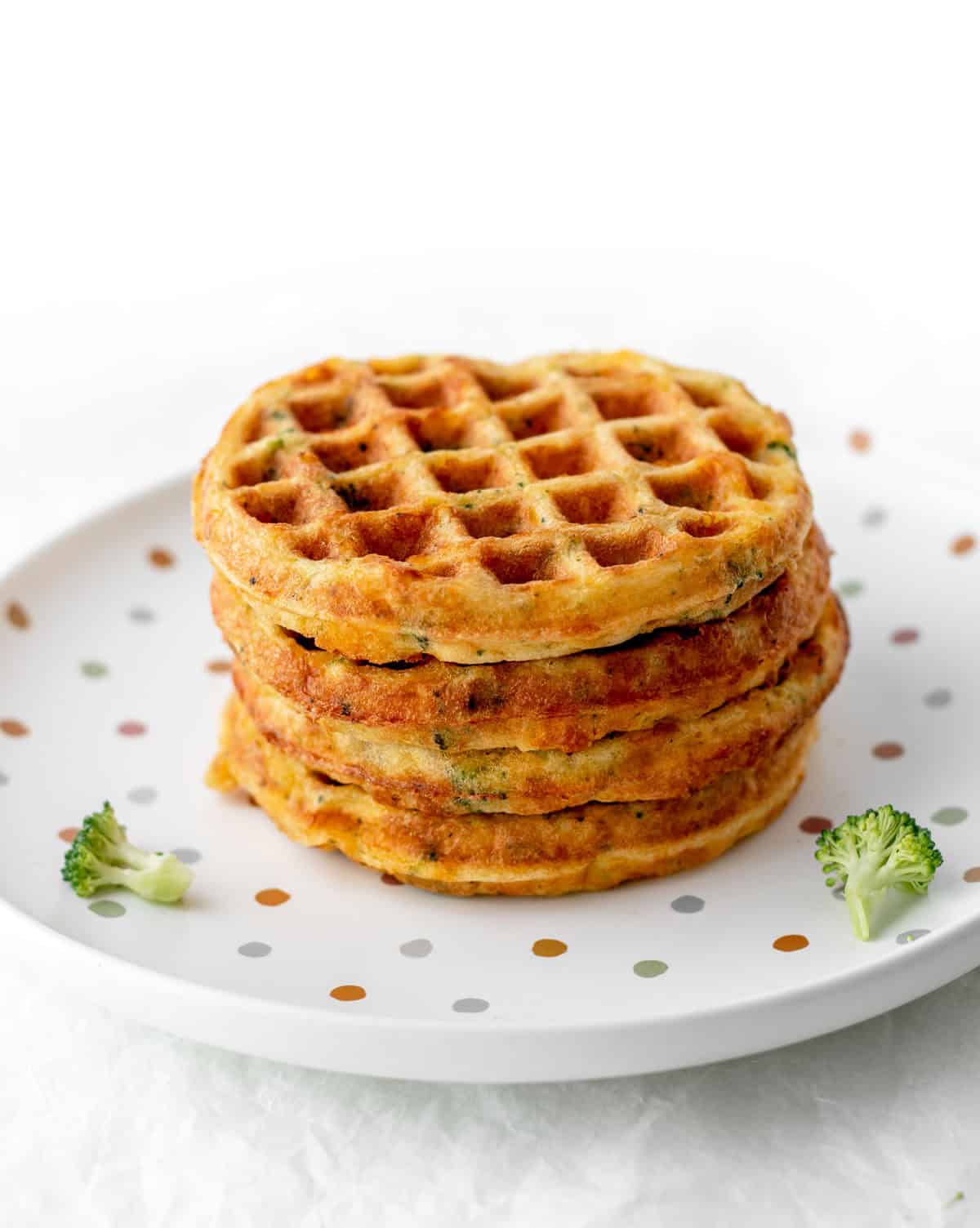 A stack of broccoli cheese waffles on a polka dot plate.