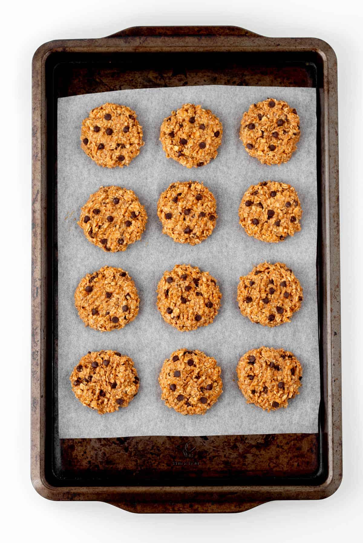 A birds-eye view of the banana pumpkin cookies with chocolate chips on a baking sheet lined with parchment paper.