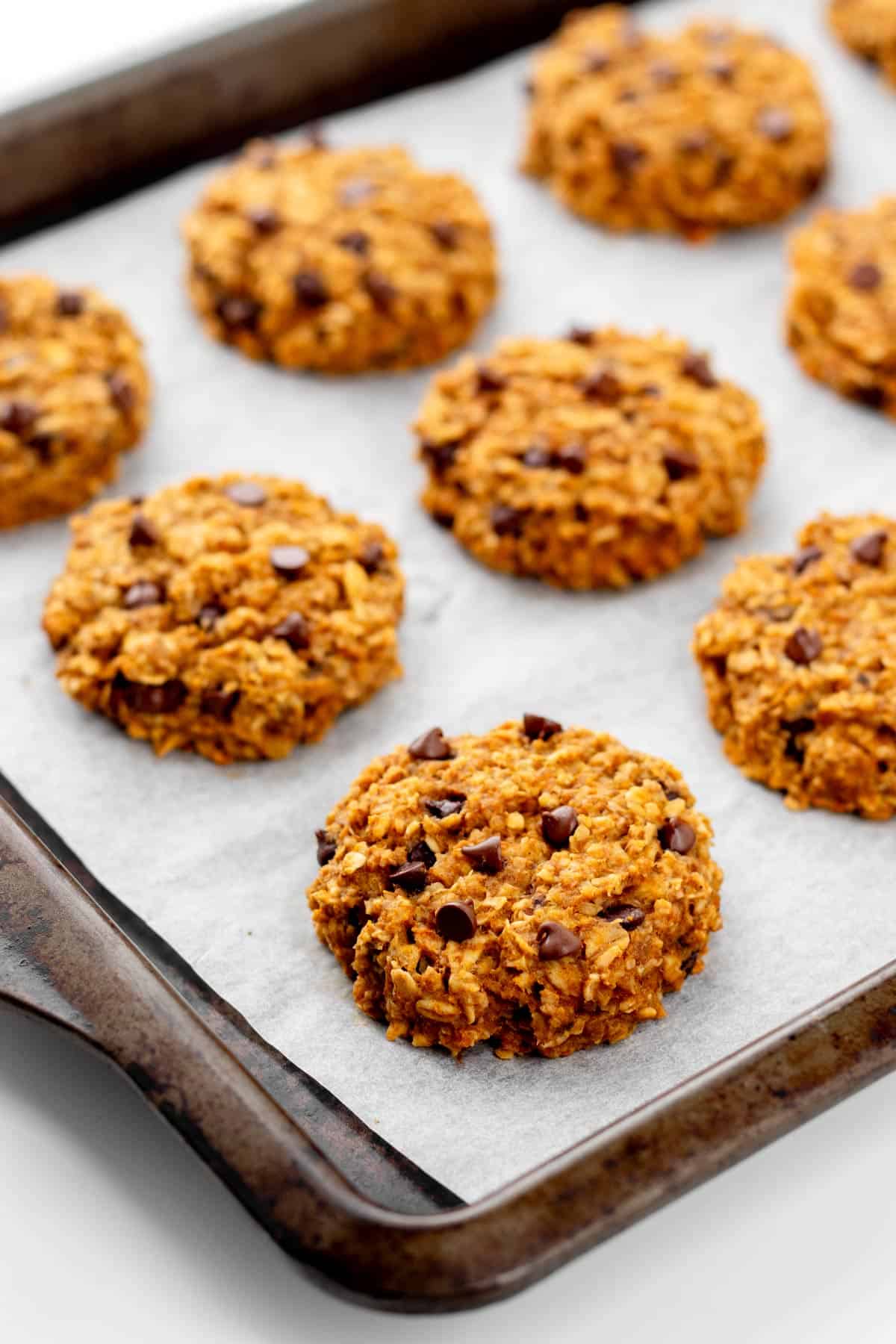 A close-up of banana pumpkin cookies on a baking sheet lined with parchment paper.