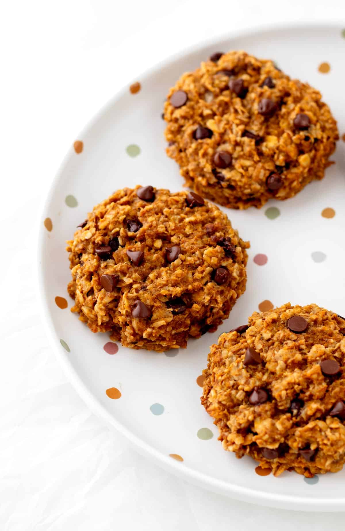 Banana pumpkin cookies with chocolate chips on a polka dot plate.