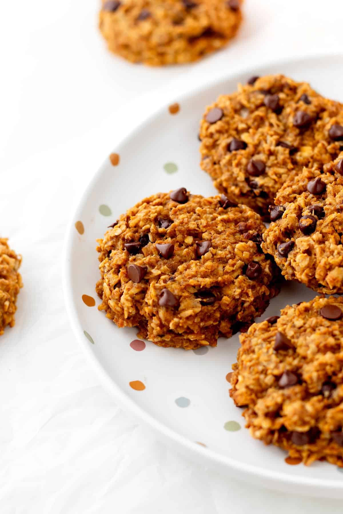 A close-up of a stack of banana pumpkin oatmeal cookies on a plate.