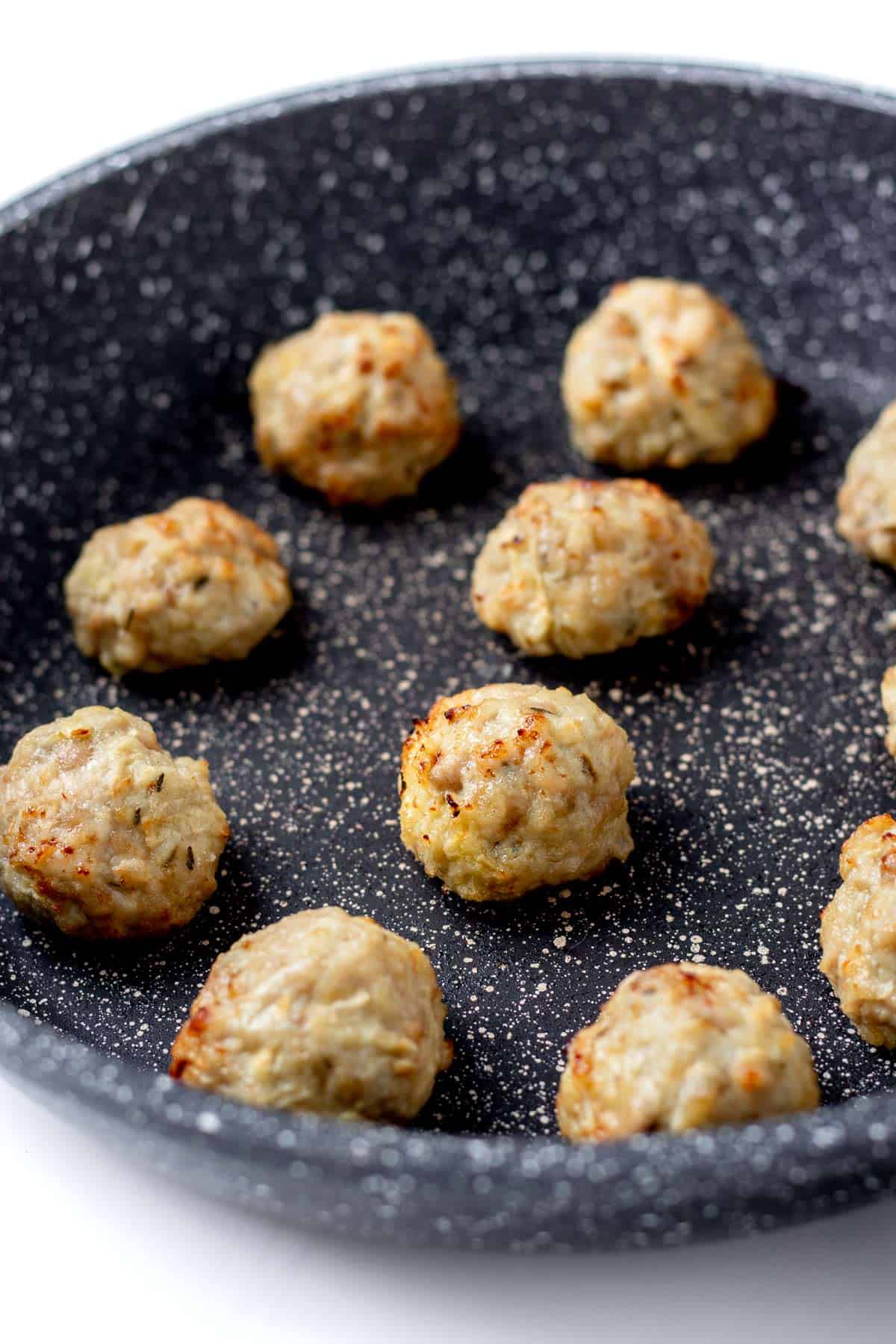 Browning the meatballs in a pan.