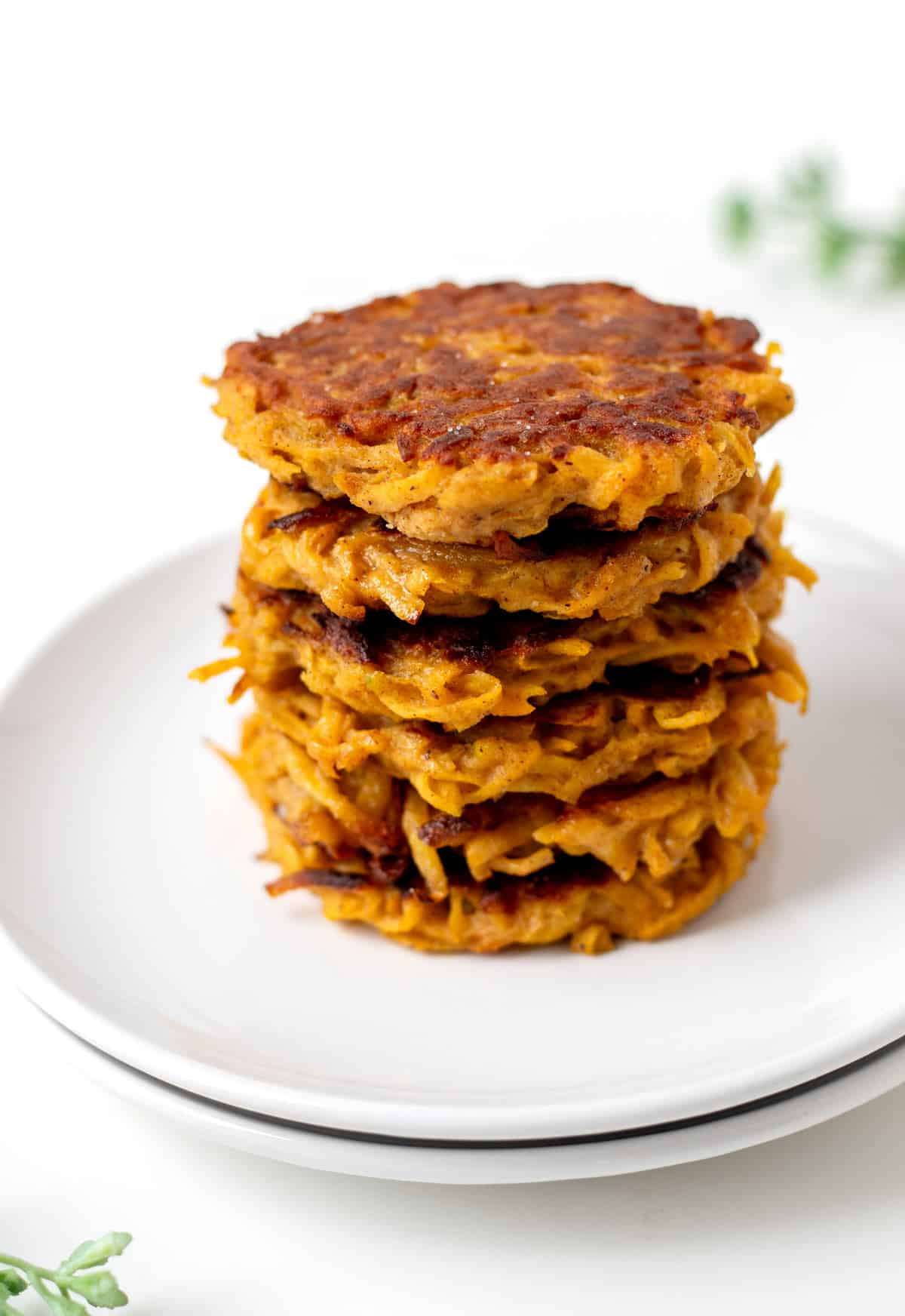 Six butternut squash cakes stacked on top of one another on a white plate.