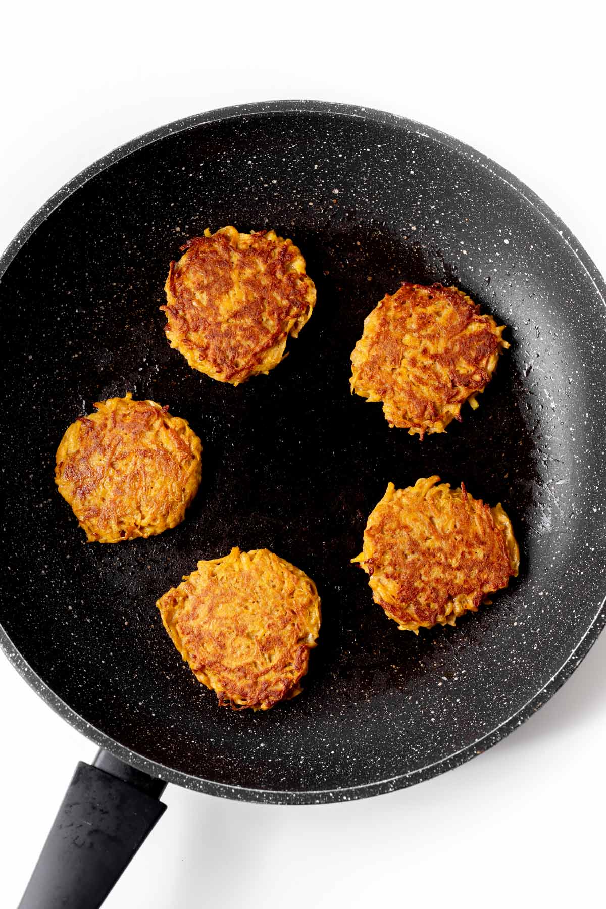 Browning the butternut squash cakes in a frying pan.